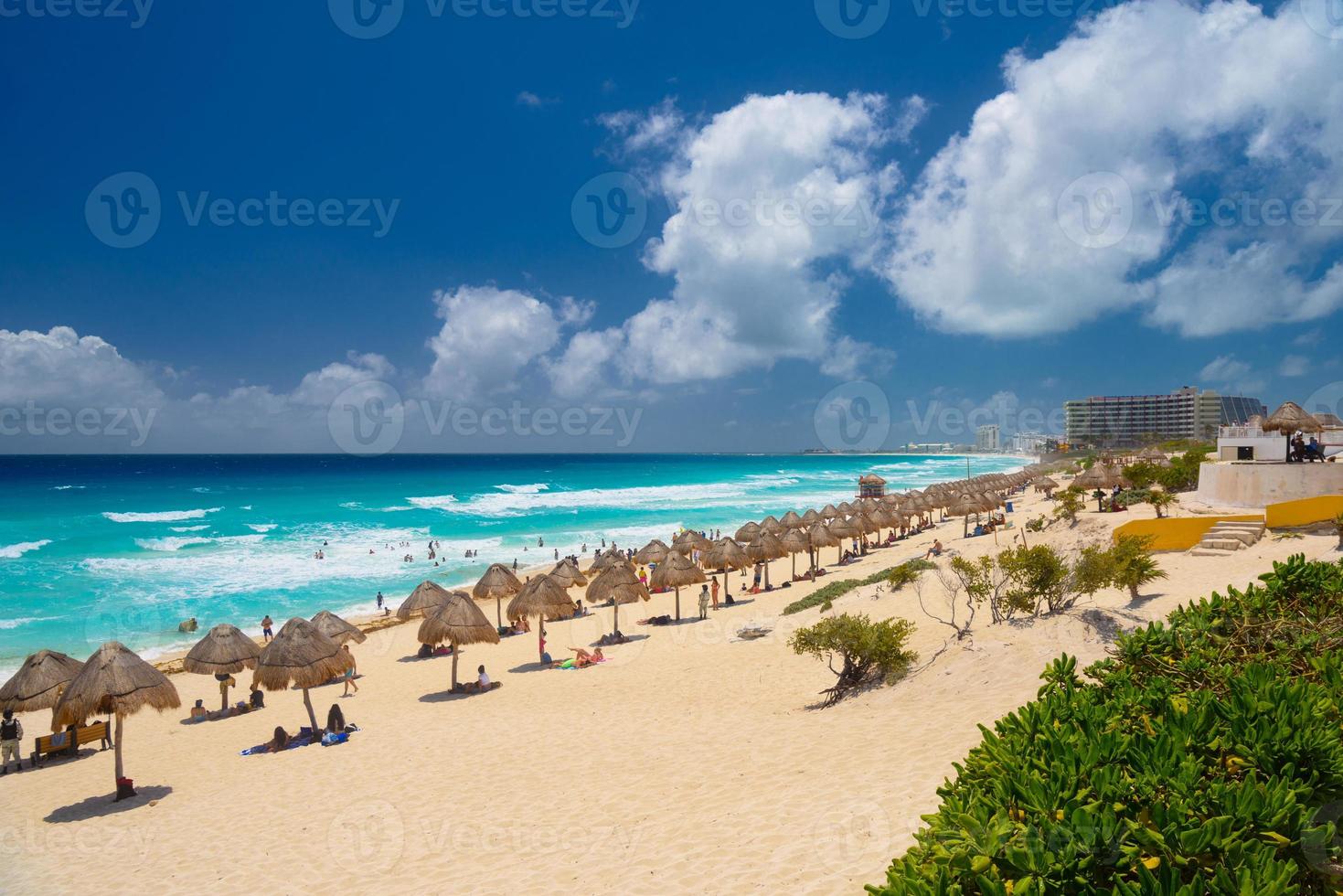 guarda-chuvas em uma praia de areia com água azul em um dia ensolarado perto de cancun, méxico foto