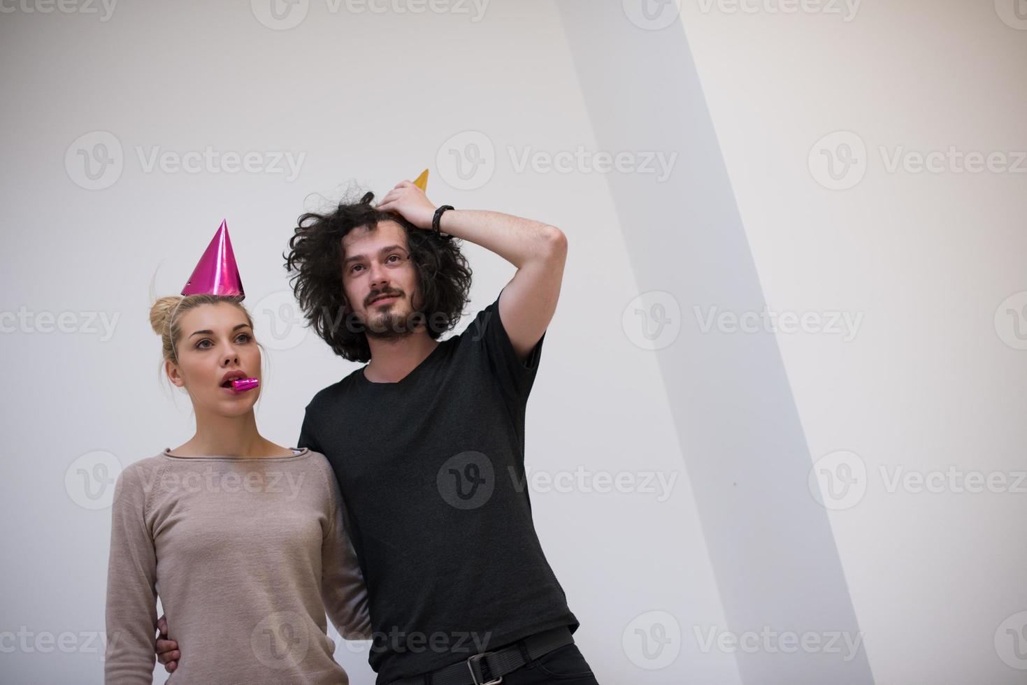 casal em chapéus de festa soprando no apito foto