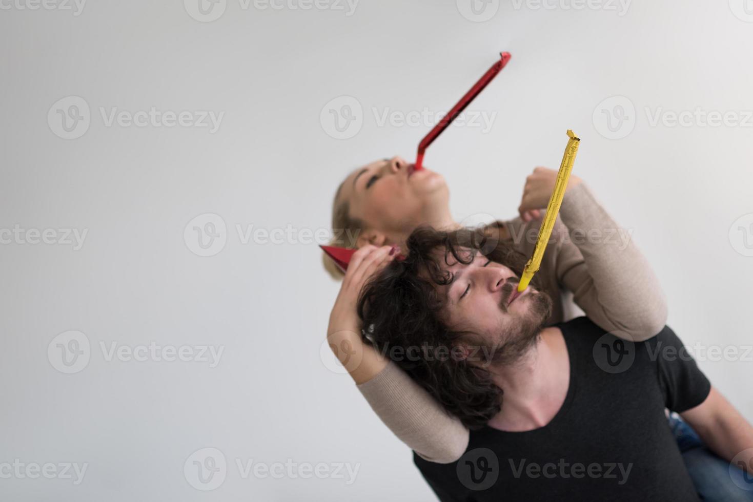 casal em chapéus de festa soprando no apito foto