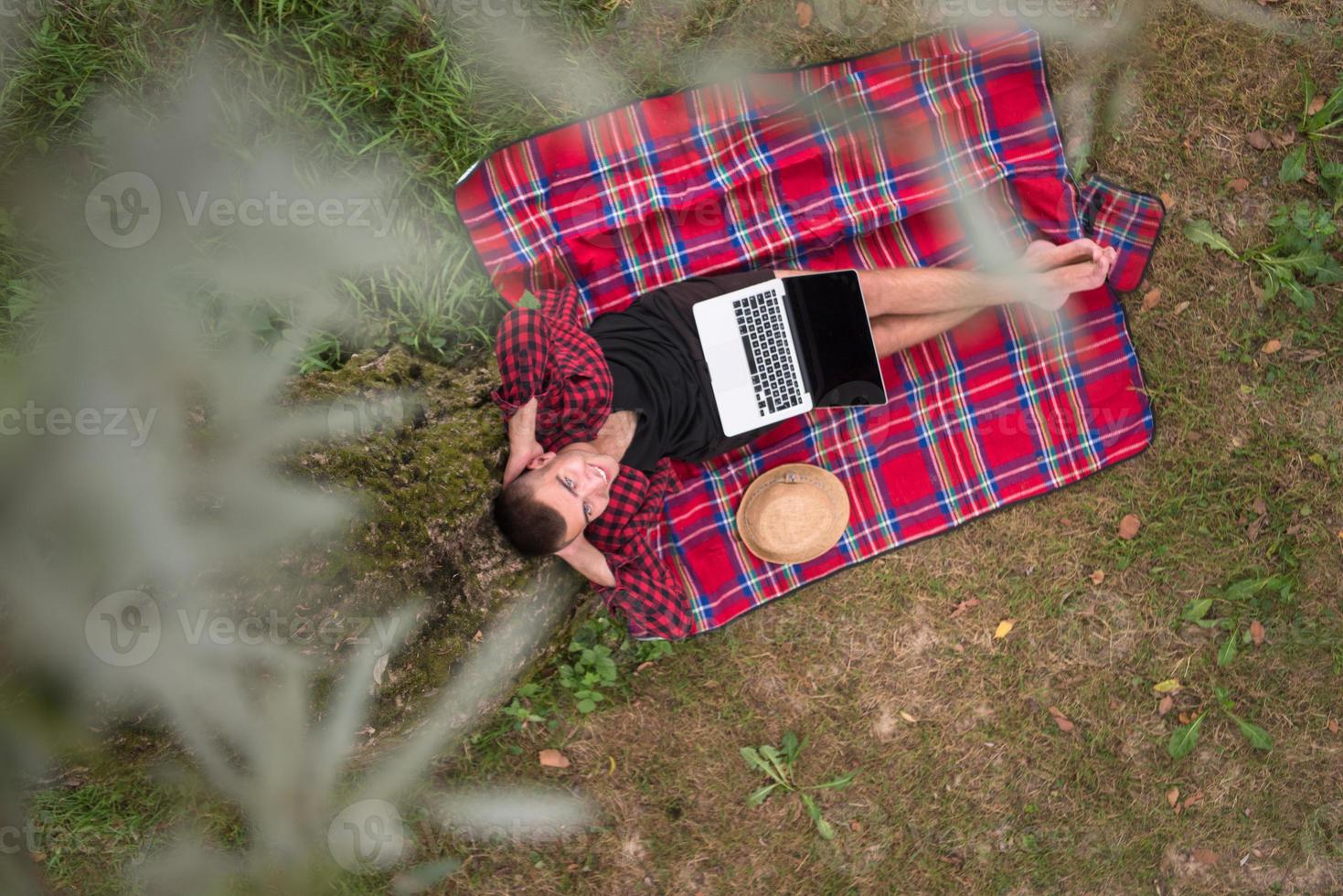 vista superior do homem usando um laptop debaixo da árvore foto