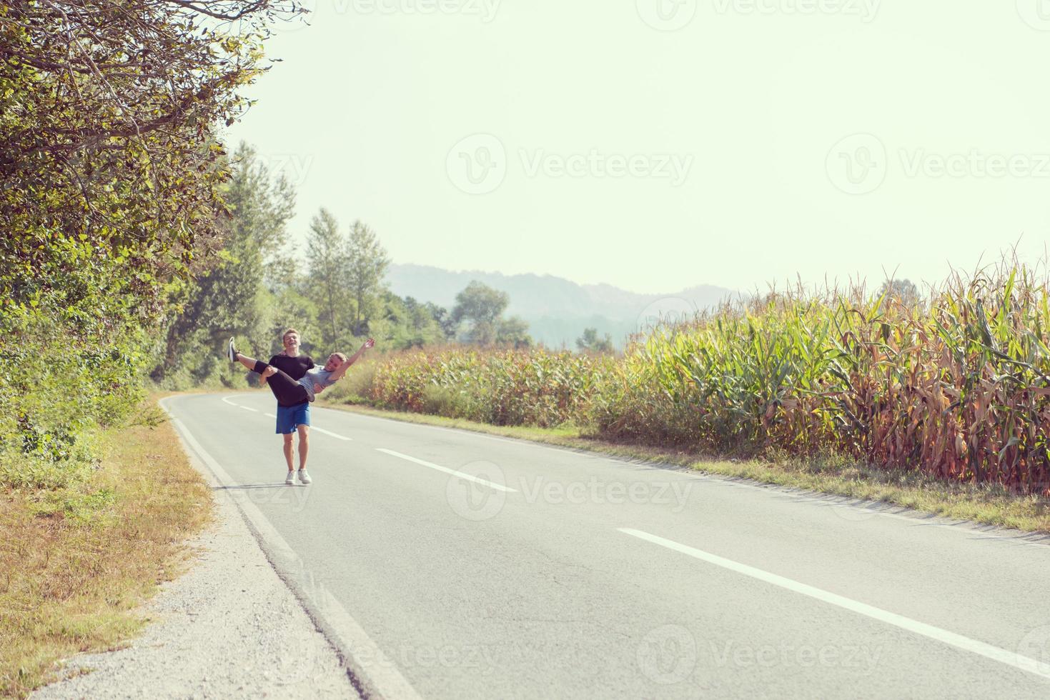 casal feliz correndo ao longo de uma estrada rural foto
