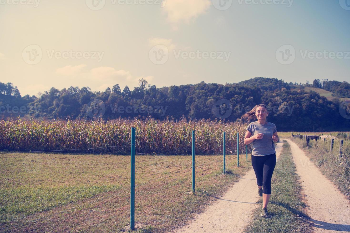 mulher correndo ao longo de uma estrada rural foto