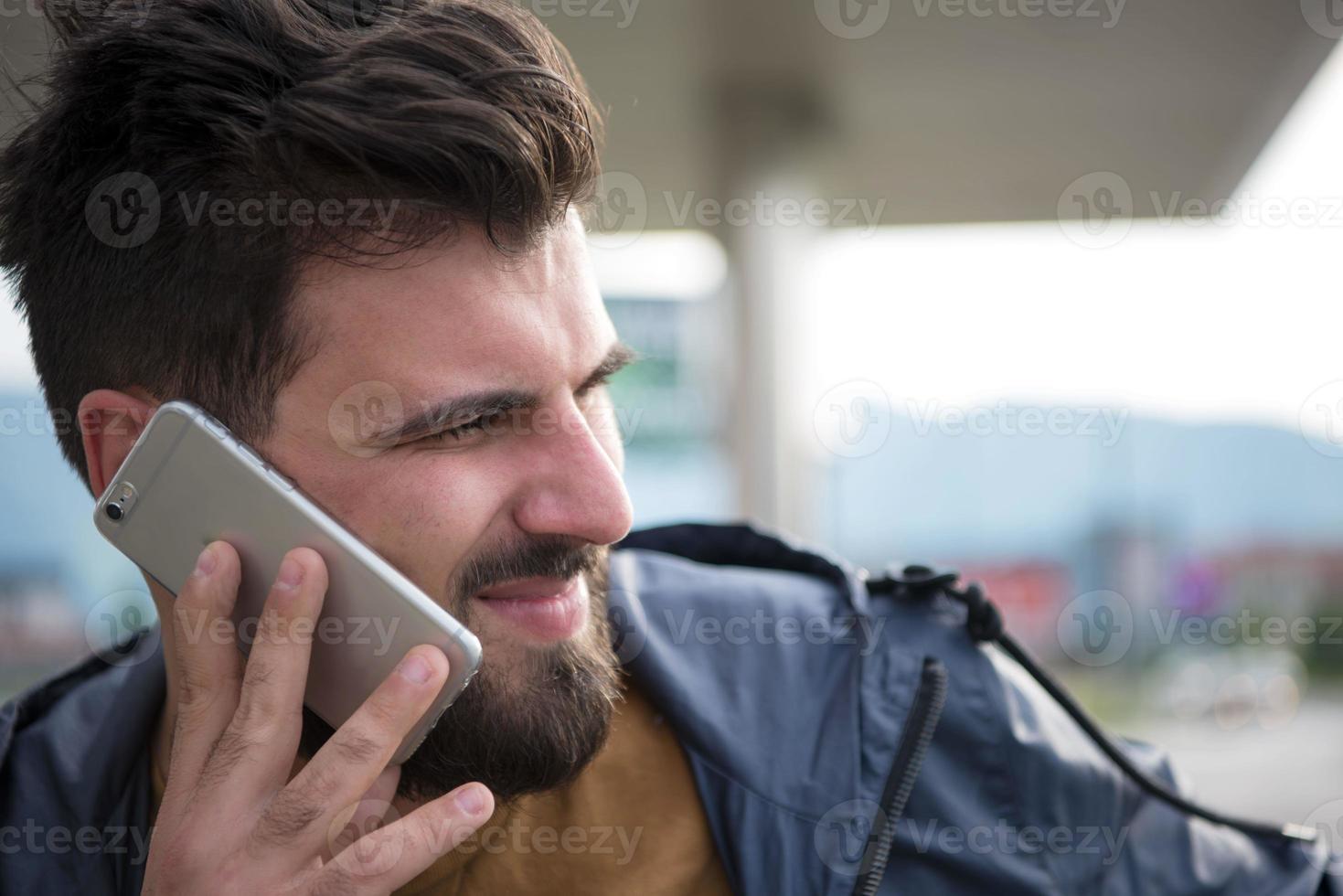 homem de negócios casual jovem bonito com barba usando telefone celular foto