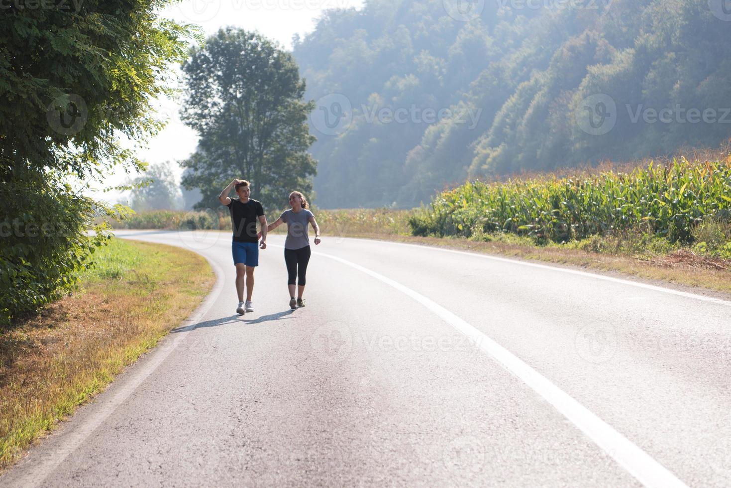 jovem casal correndo ao longo de uma estrada rural foto