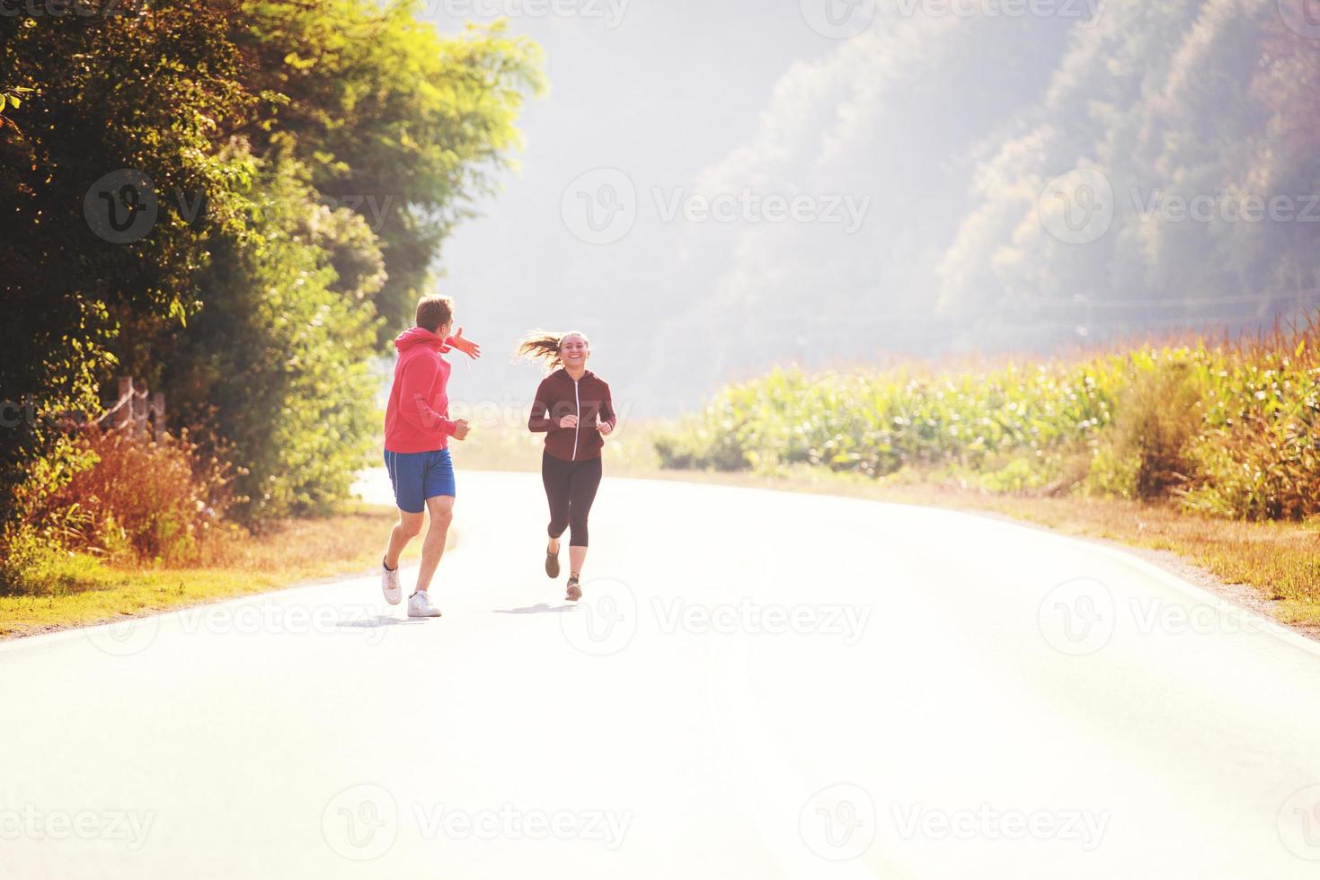 jovem casal correndo ao longo de uma estrada rural foto