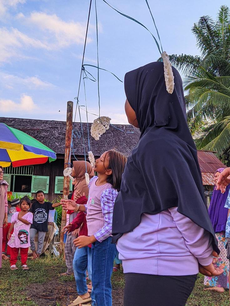 a emoção de adultos e crianças participando de uma competição de comer biscoitos para animar o dia da independência da república da indonésia, kalimantan oriental, indonésia 13 de agosto de 2022 foto