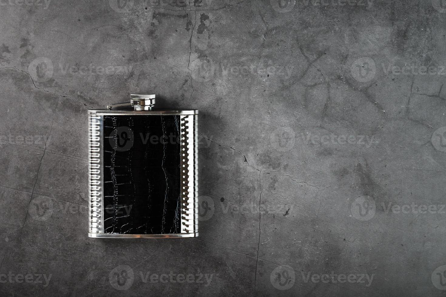 frasco de aço em acabamento de couro para álcool em um fundo escuro com espaço de cópia foto