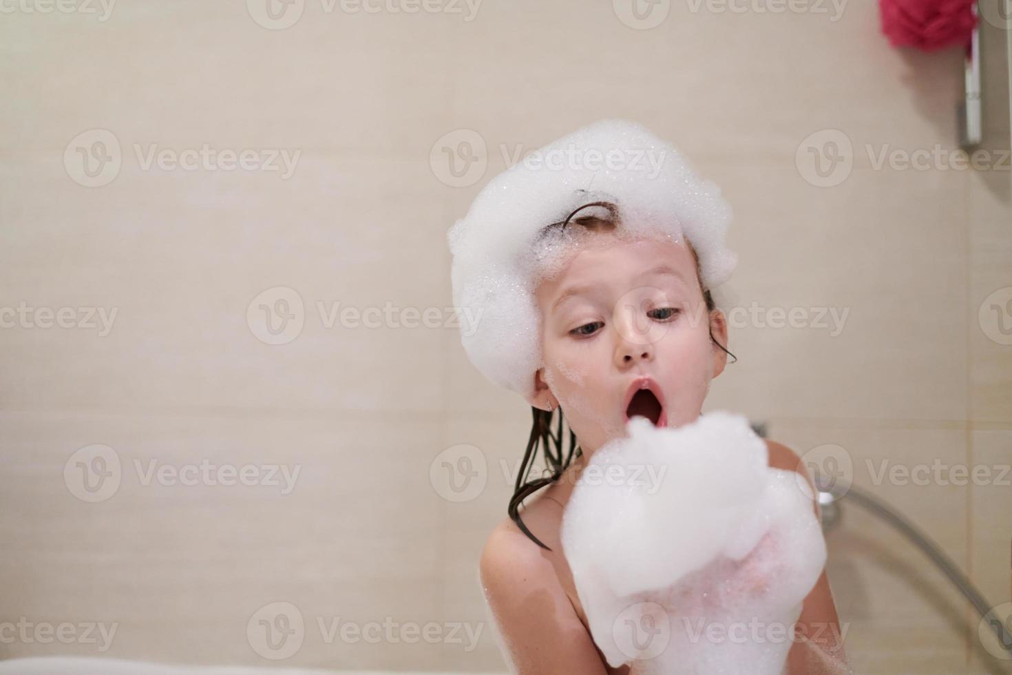 menina no banho brincando com espuma de sabão foto