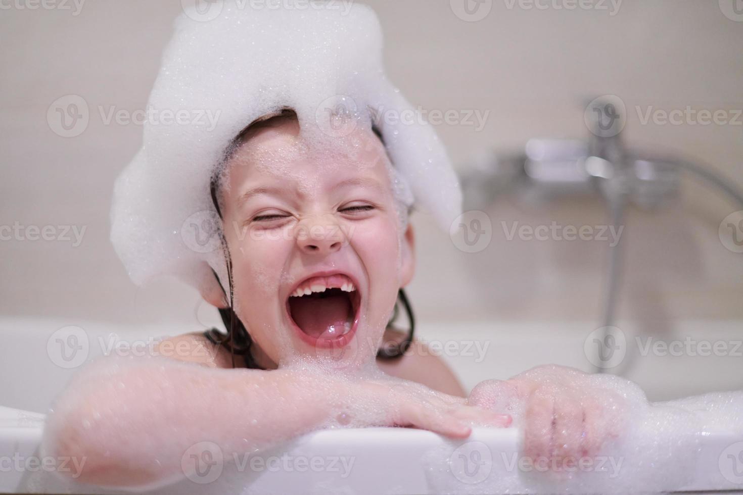 menina no banho brincando com espuma de sabão foto