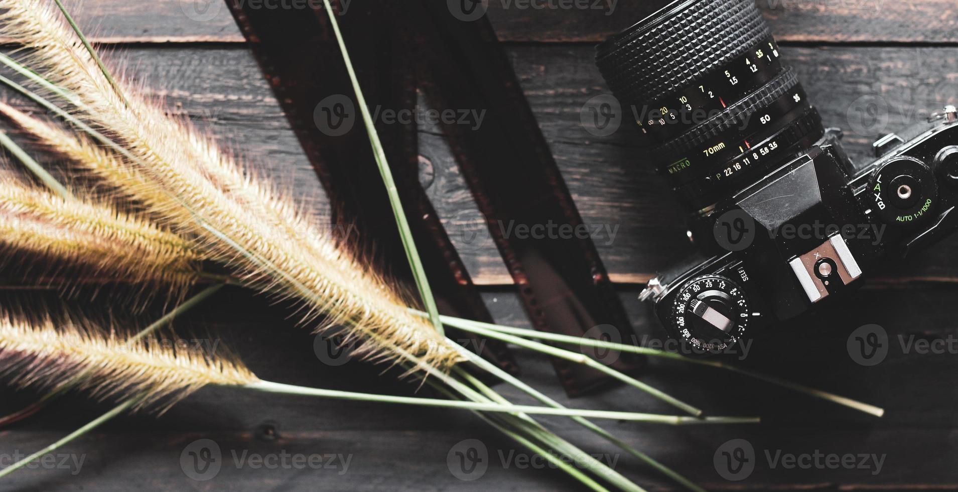 câmera de filme retrô e filme negativo em uma mesa de madeira preta foto