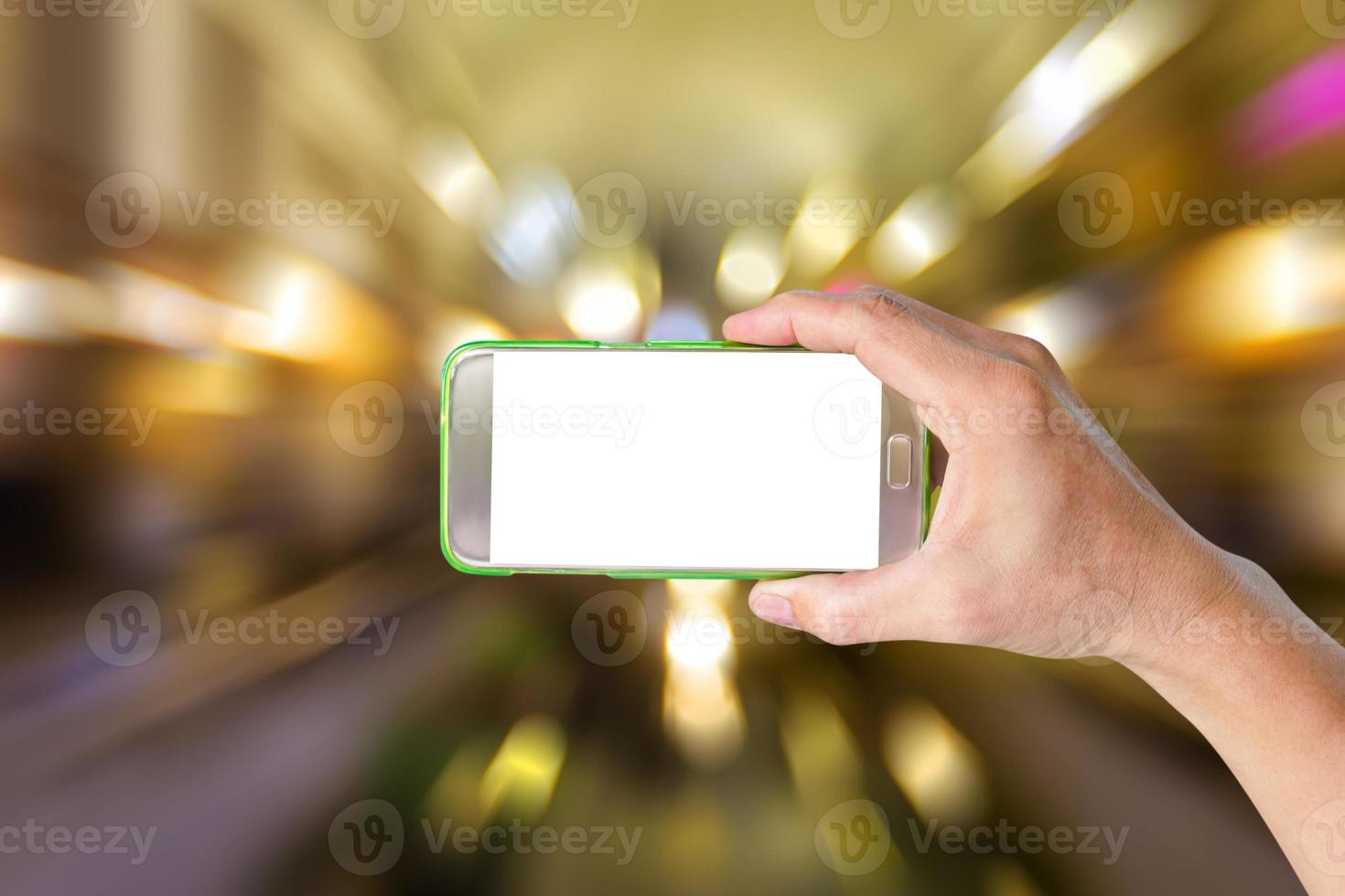 mão segurando o telefone inteligente móvel com fundo de desfoque de movimento bokeh foto