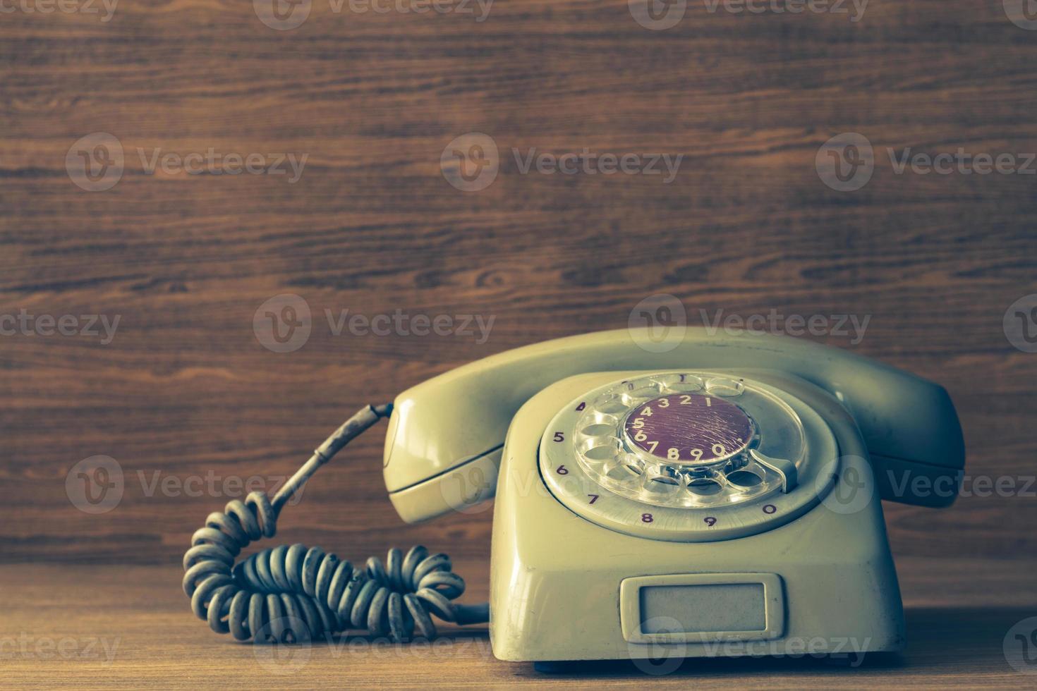 telefone antigo no fundo da mesa de madeira. tom vintage foto