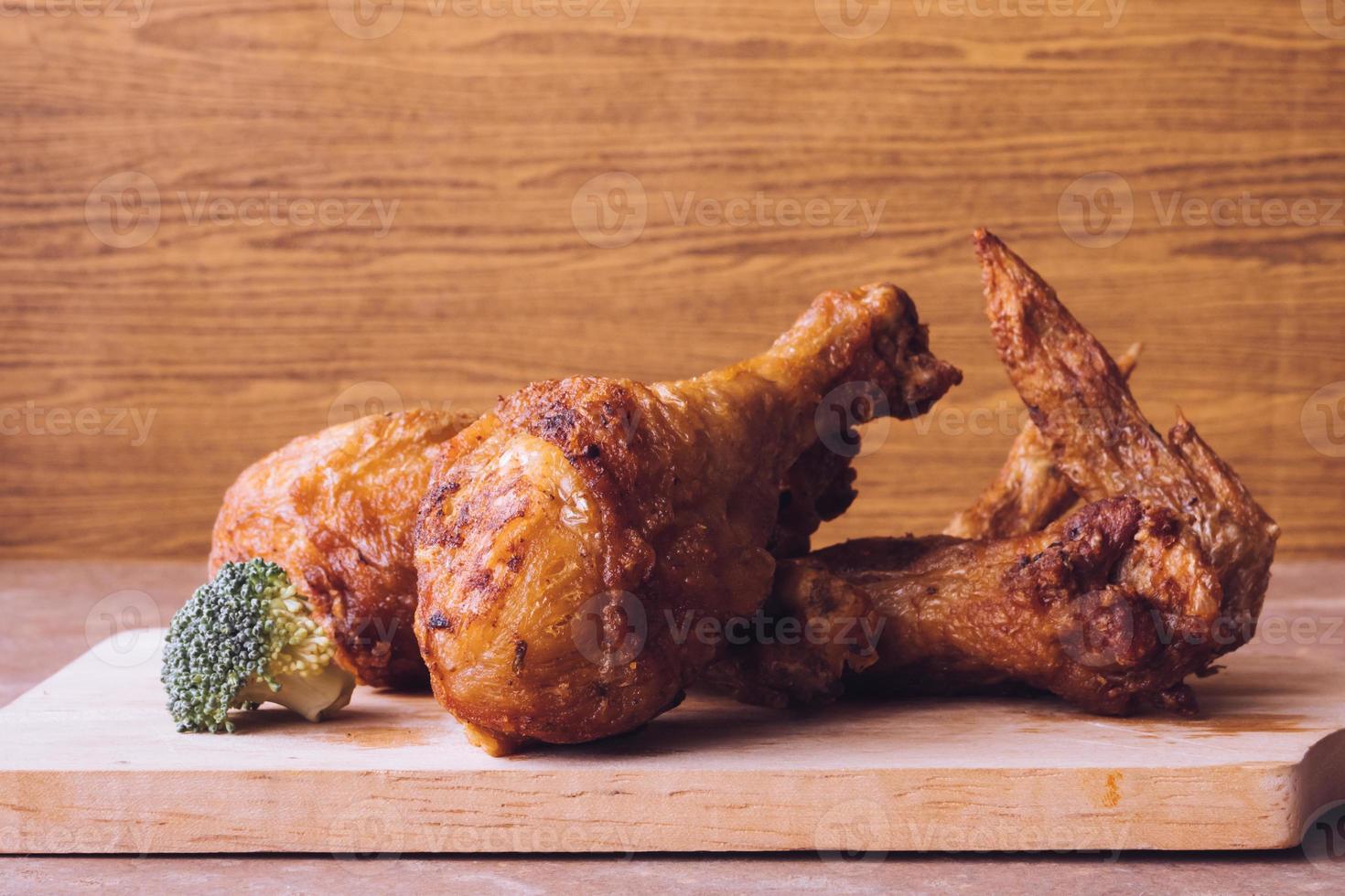 pernas de frango frito e asas na bandeja de madeira. foto