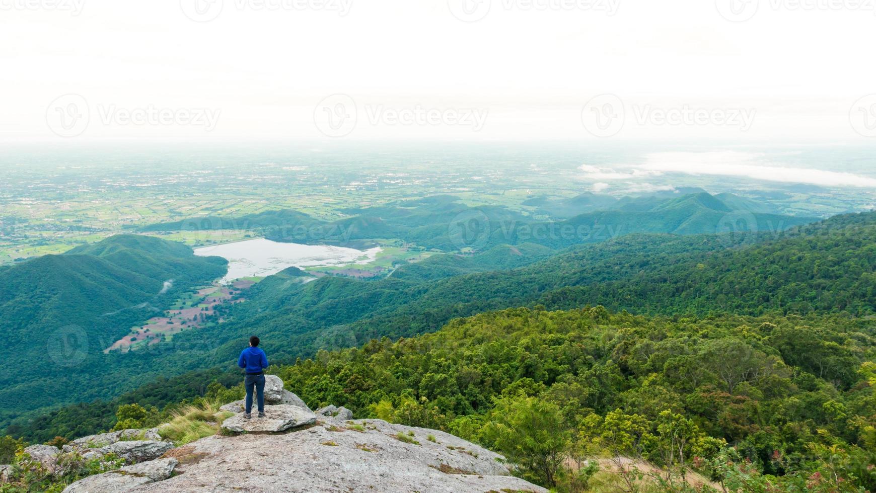 jovem desfrutando de uma vista do vale do topo de uma montanha. foto