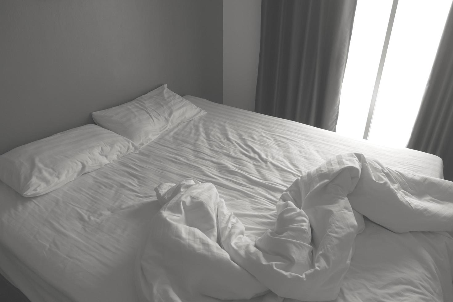 lençóis e travesseiros brancos bagunçados. tom preto e branco foto
