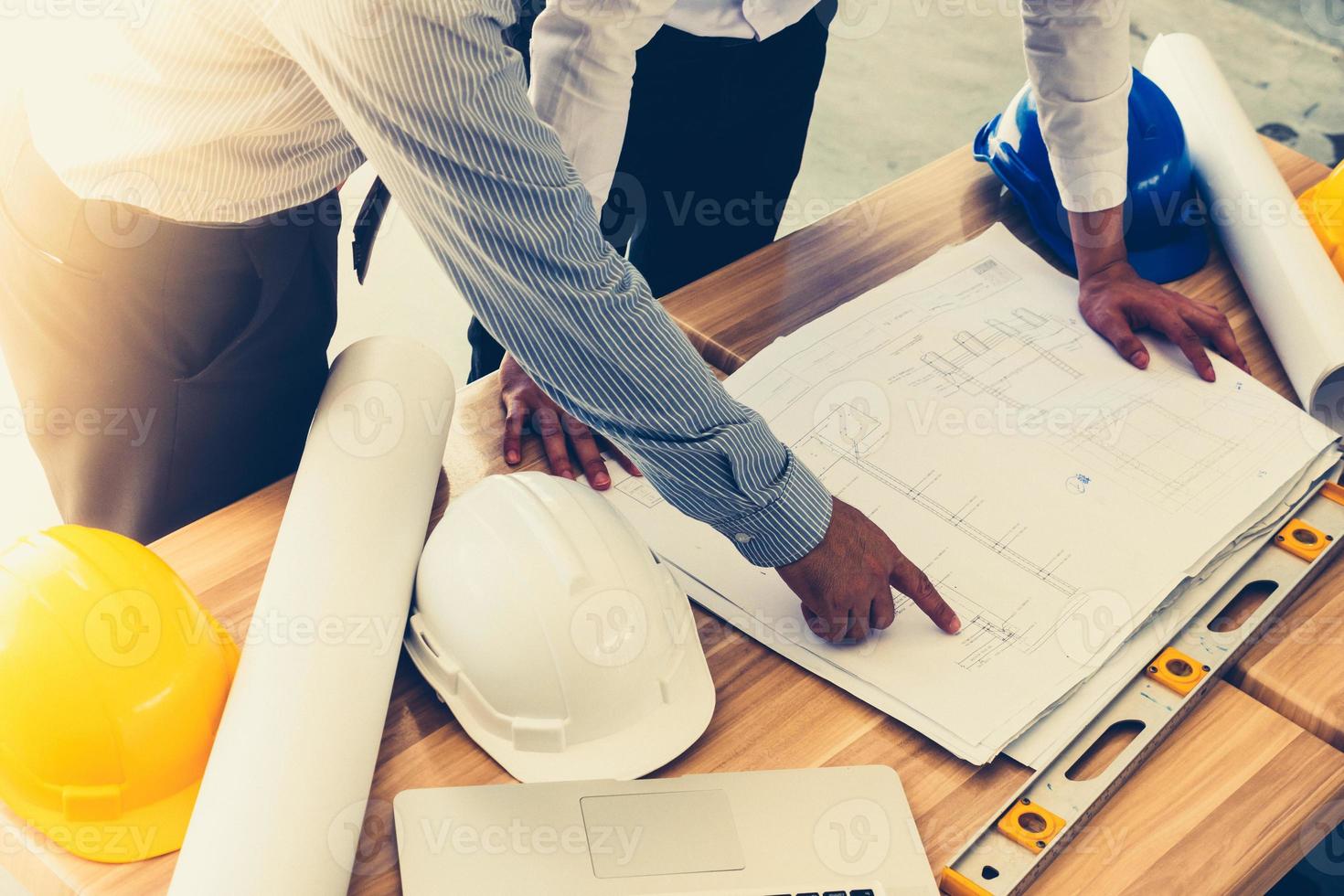 equipe de engenheiros discutindo o esboço do plano de arquitetura no canteiro de obras. tom vintage foto