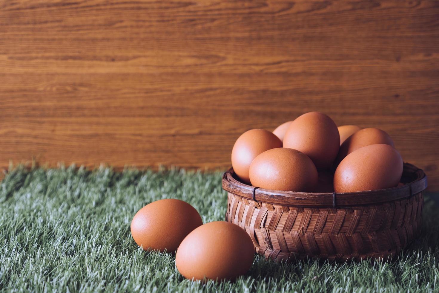 ovos na cesta de madeira na grama verde. espaço livre para texto foto