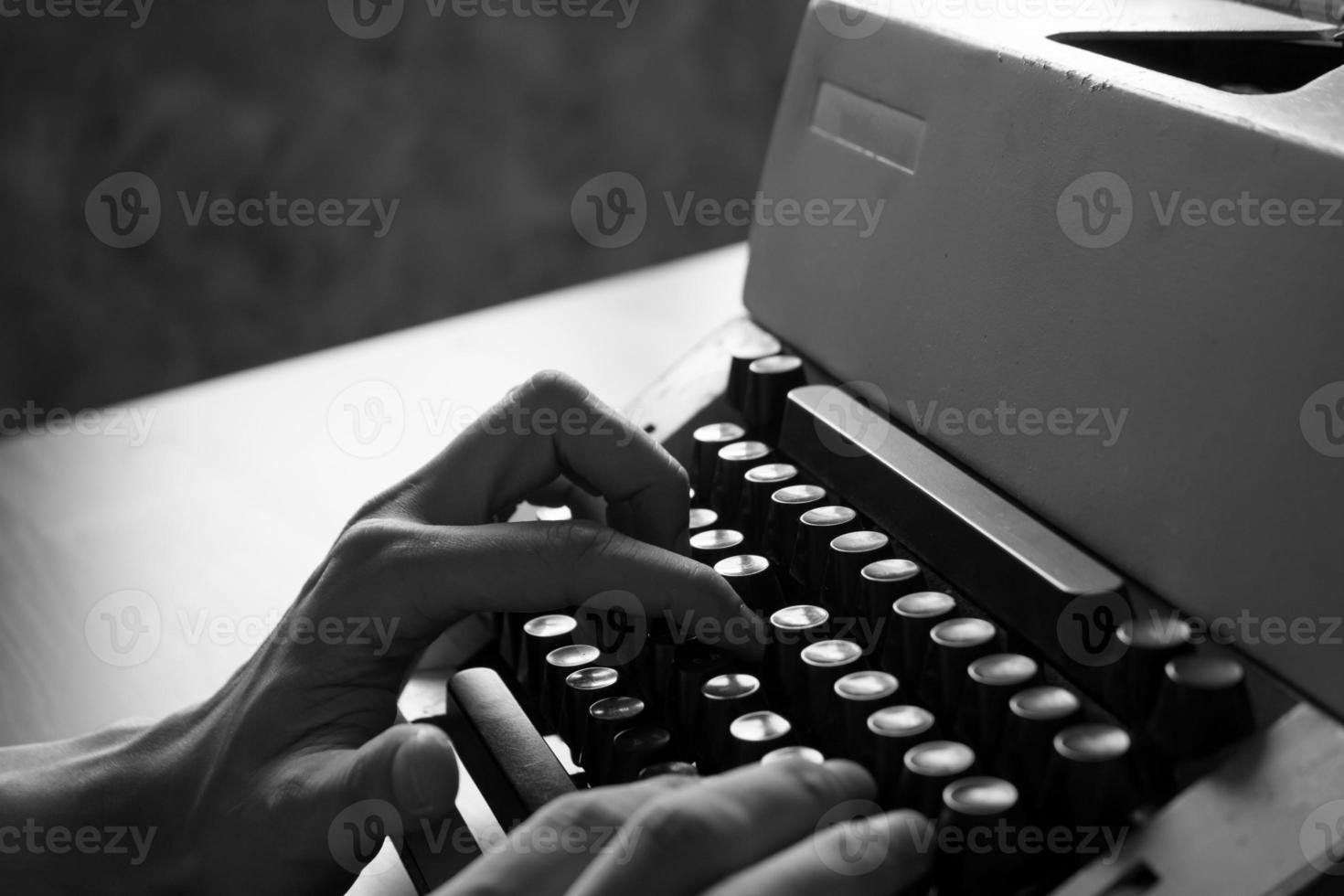 close-up de mãos masculinas digitando na velha máquina de escrever. tom preto e branco foto