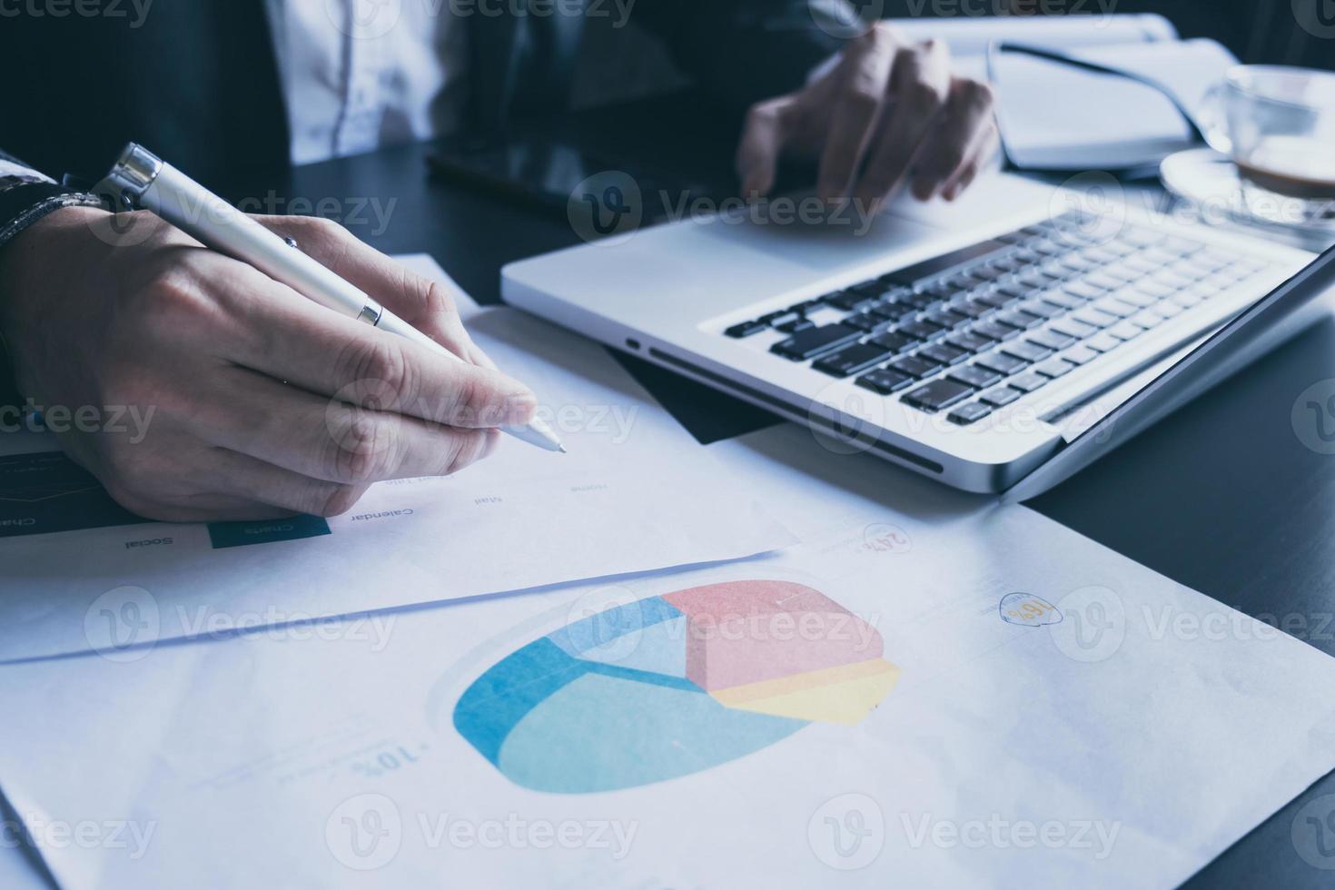 close-up do empresário usando laptop e analisando gráficos de investimento na mesa do escritório. foto