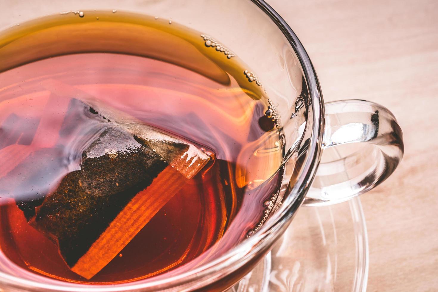 uma xícara de chá na mesa de madeira, saquinho de chá em vidro. foto