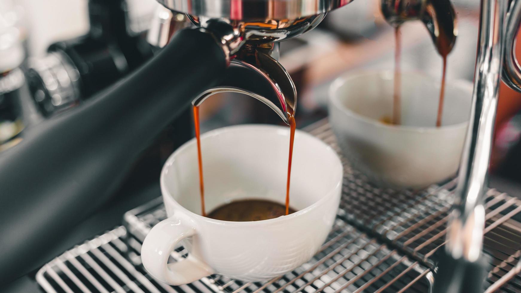 close-up de café expresso derramando da máquina de café fluindo para a xícara de café fazer café para os clientes no café. foto