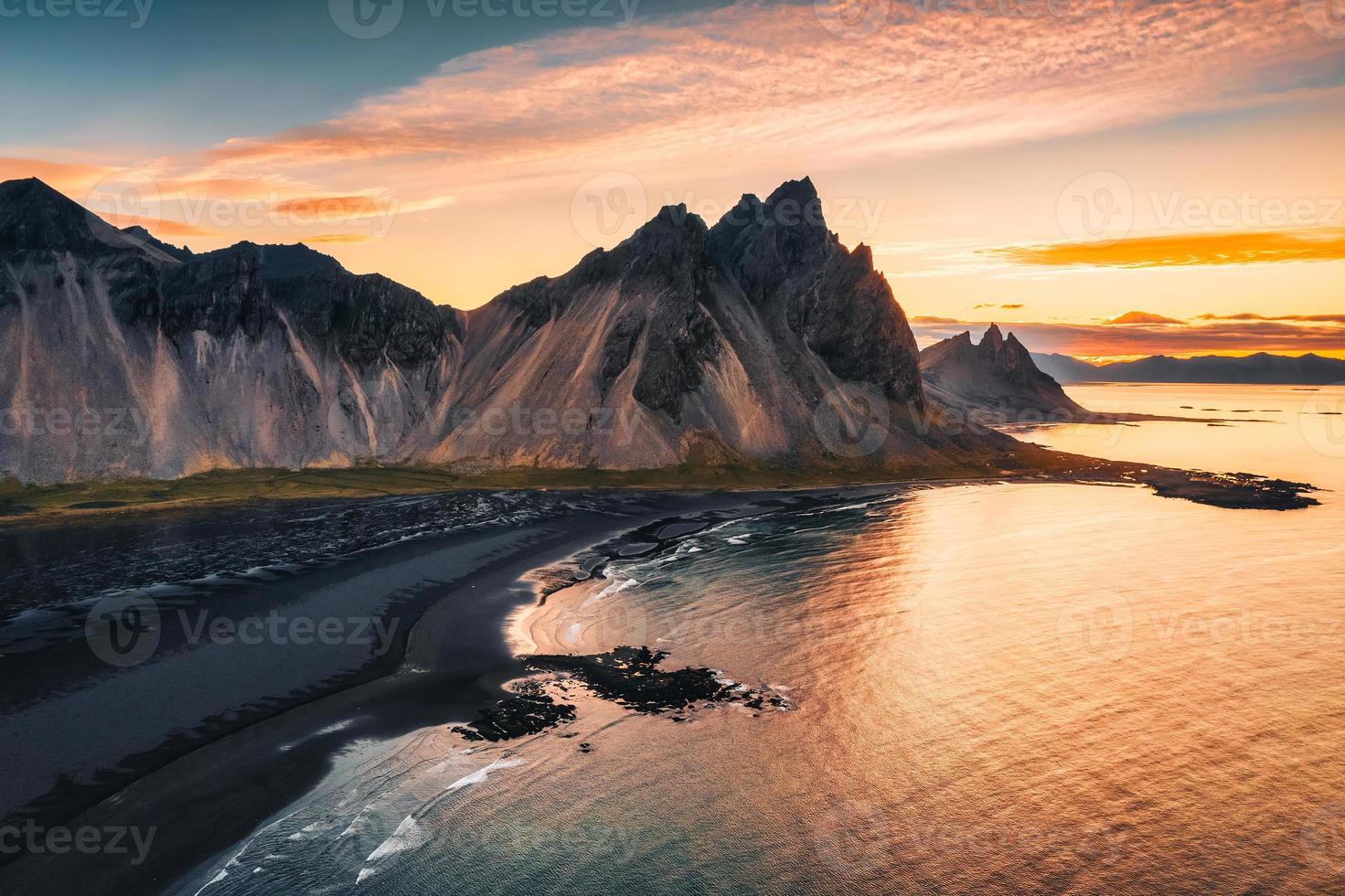 belo nascer do sol sobre a montanha vestrahorn e a praia de areia preta no oceano atlântico em stokksnes no sudeste da islândia foto