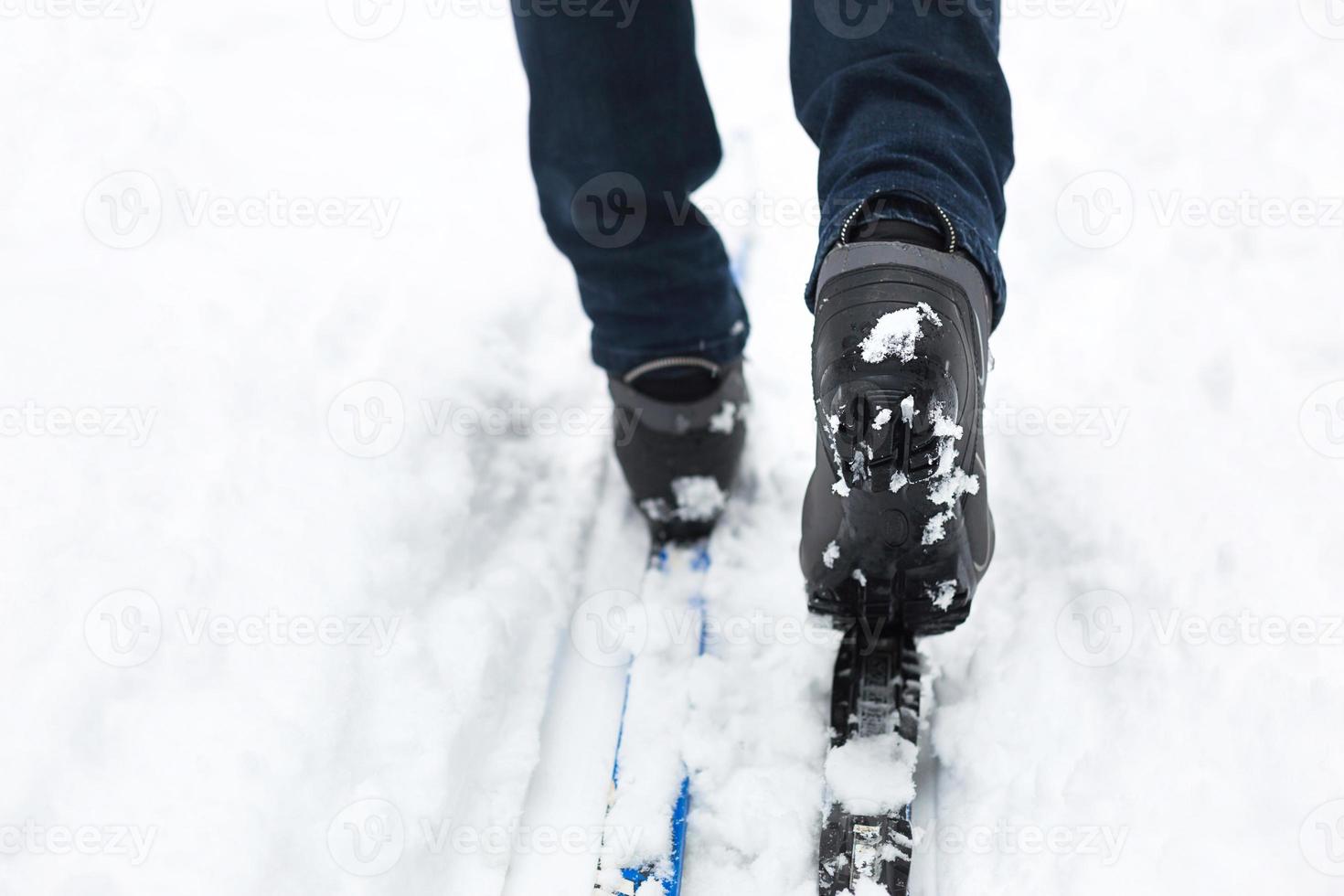 pés de um esquiador em botas de esqui em esquis cross-country. andando na neve, esportes de inverno, estilo de vida saudável. close-up, copyspace foto