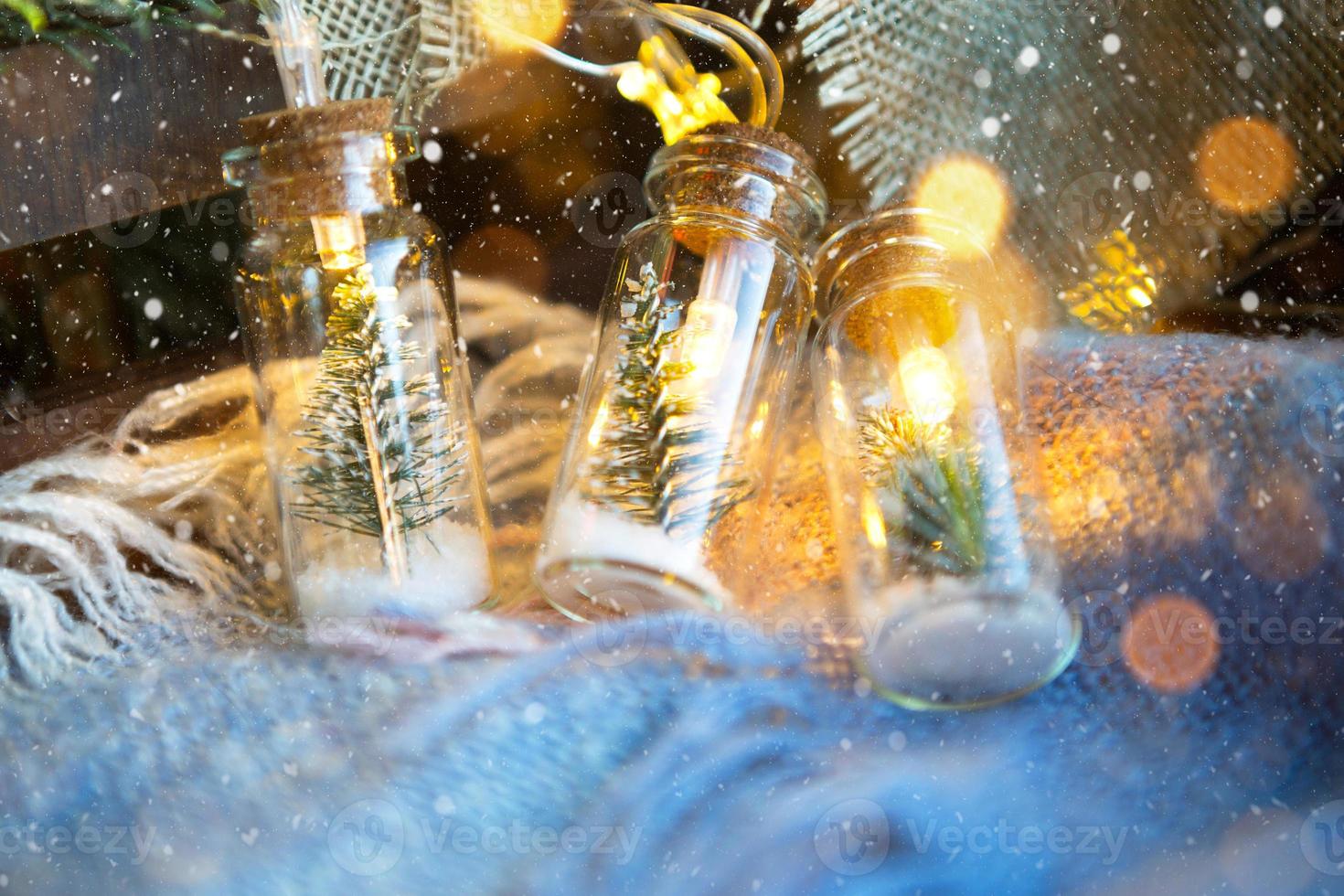 luzes de fada em uma jarra com uma árvore de natal e close-up de neve em uma manta aconchegante e aconchegante com decoração de madeira. natal e ano novo, decoração festiva, conforto em casa, preparação para celebração, clima fabuloso foto