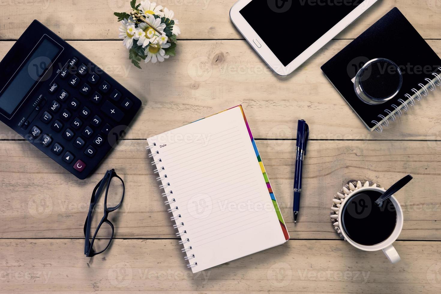 caderno com caneta e equipamento de escritório na área de trabalho foto