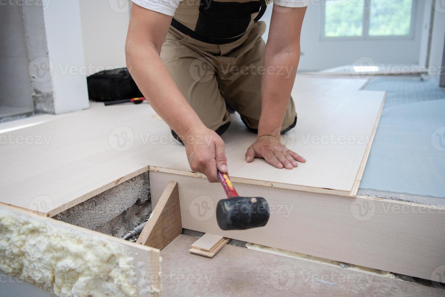 trabalhador profissional instalando novo piso de madeira laminado foto