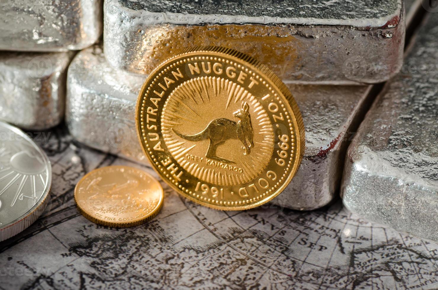 pepita de moeda de ouro australiano na frente de barras de prata foto