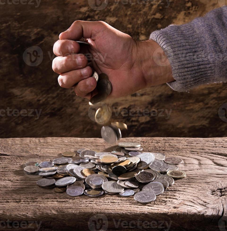 mãos do homem caucasiano e pilha de moedas antigas foto