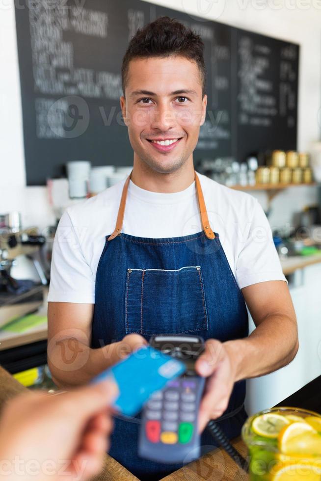 homem segurando o leitor de cartão de crédito no café foto