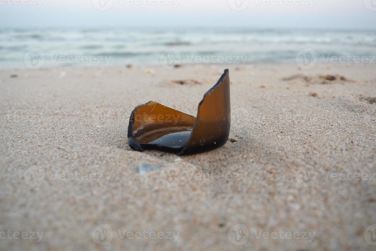 desperdício de garrafa quebrada no fundo de areia do mar foto