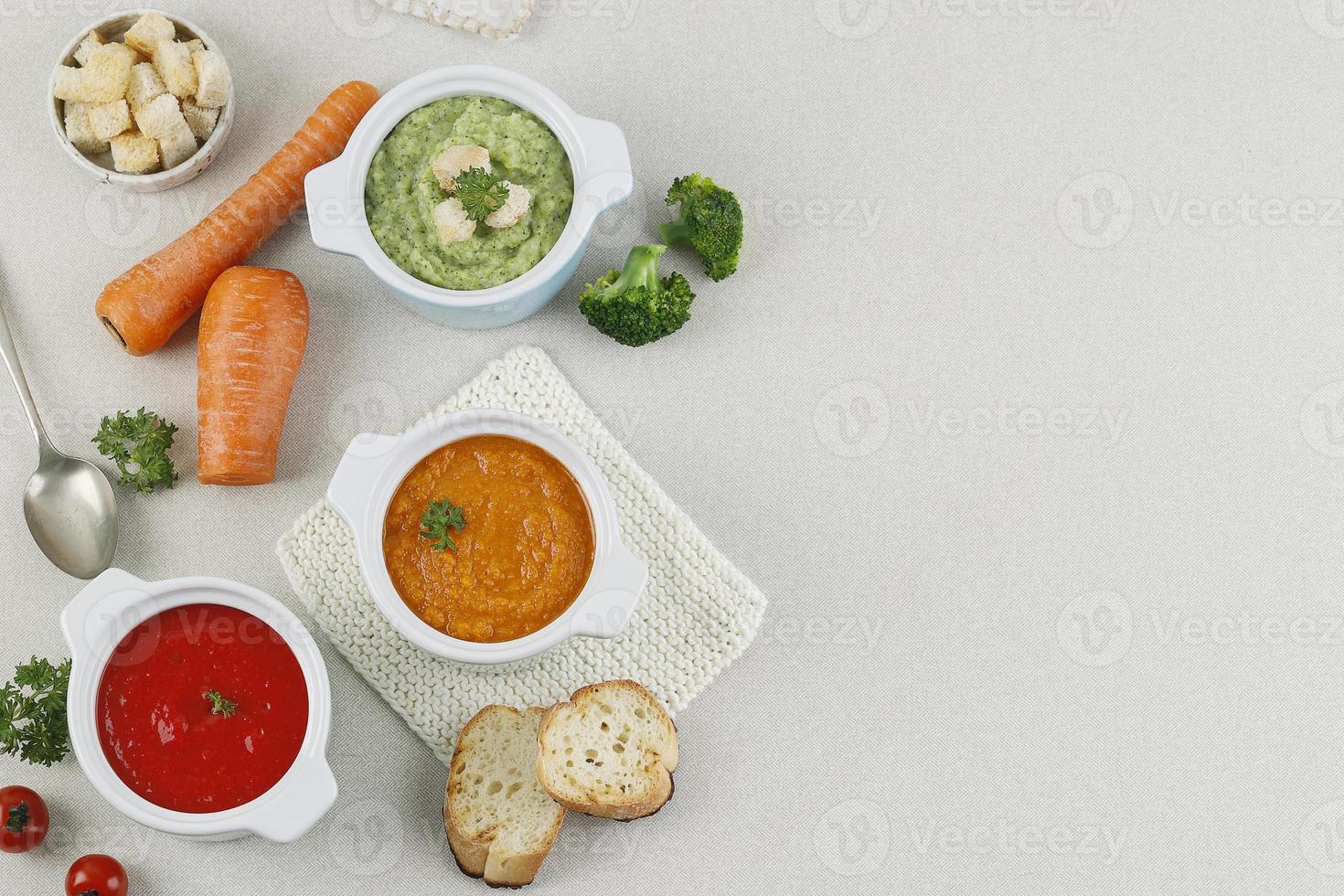 vista superior várias sopas de legumes, brócolis, tomate e, sopa de cenoura com croutons e pão. dieta saudável conceito foto