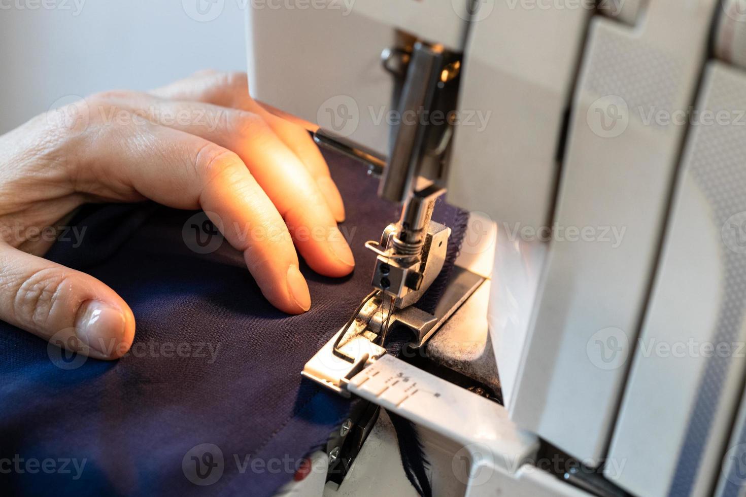 costureira processa a borda do tecido em serger foto