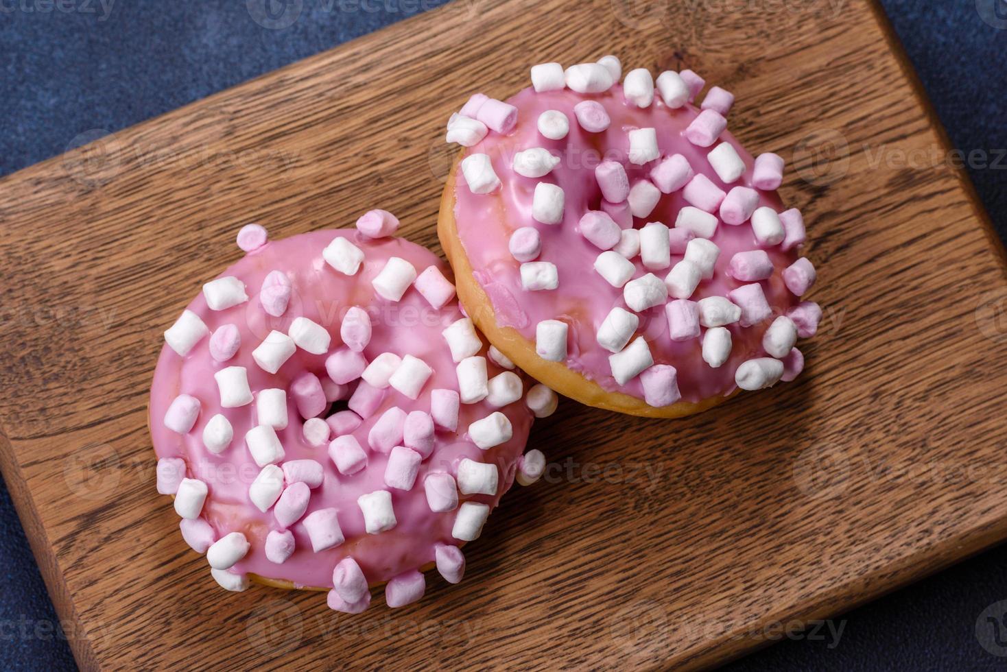 rosquinha vitrificada rosa e marshmallow com decorações de natal em uma tábua de madeira foto