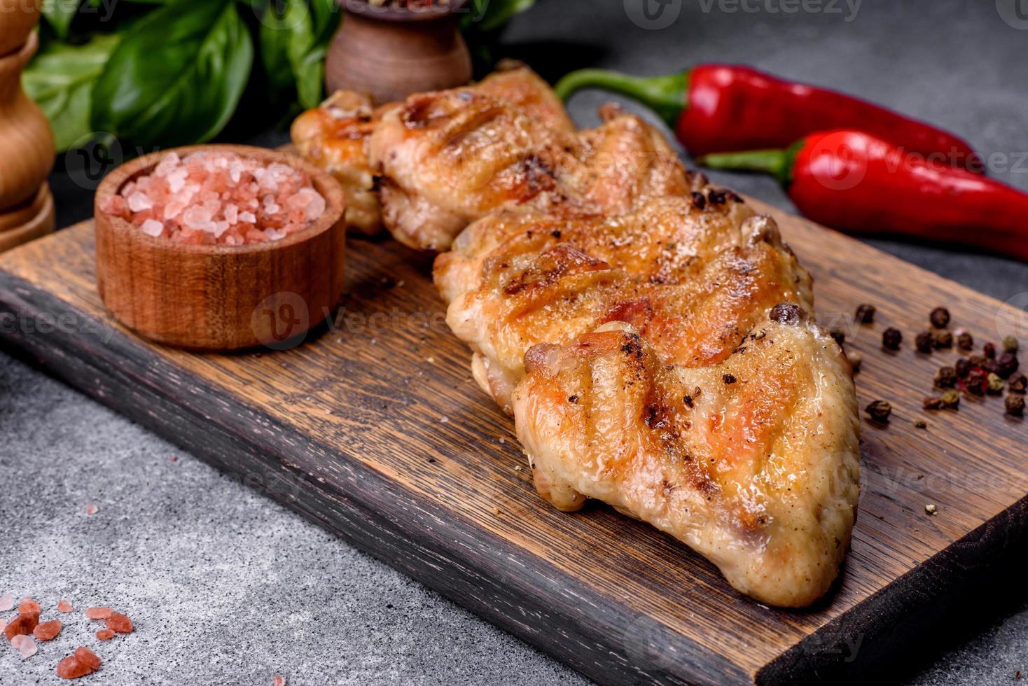 asas de frango assadas com sementes de gergelim e molho em uma tábua de madeira foto