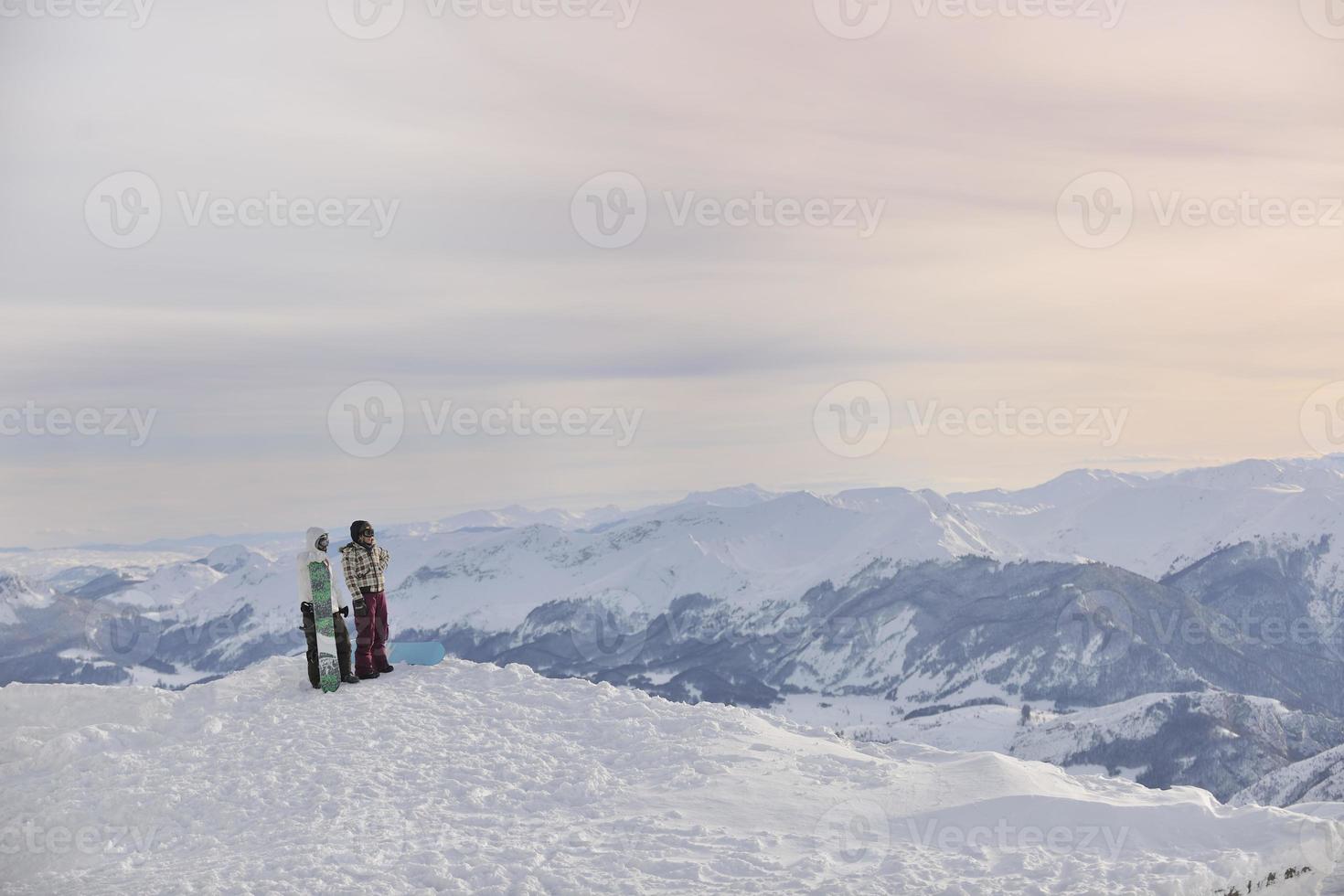 casal de snowboarder no topo da montanha foto