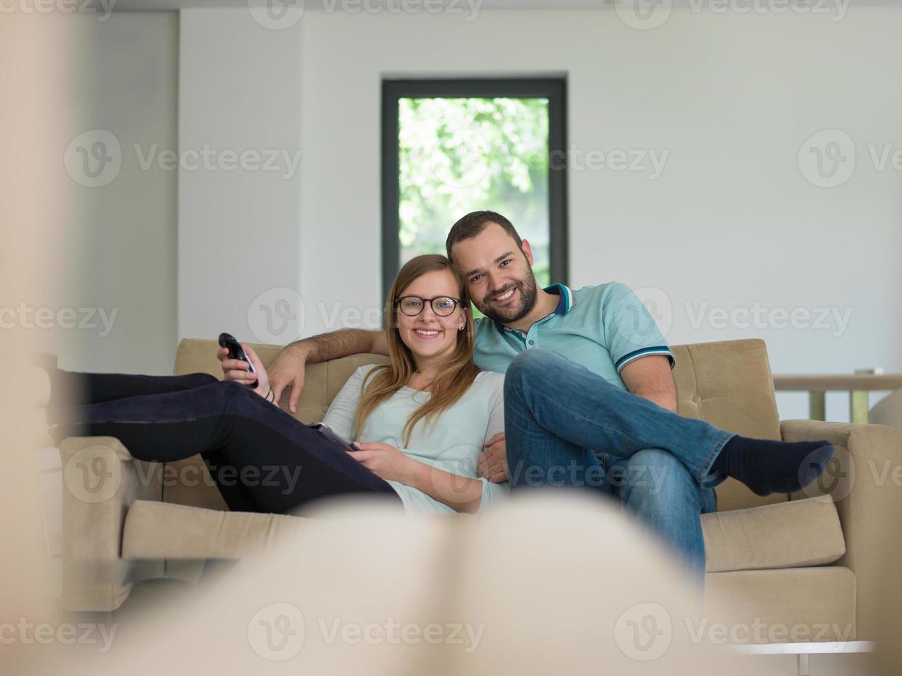 jovem casal no sofá assistindo televisão foto