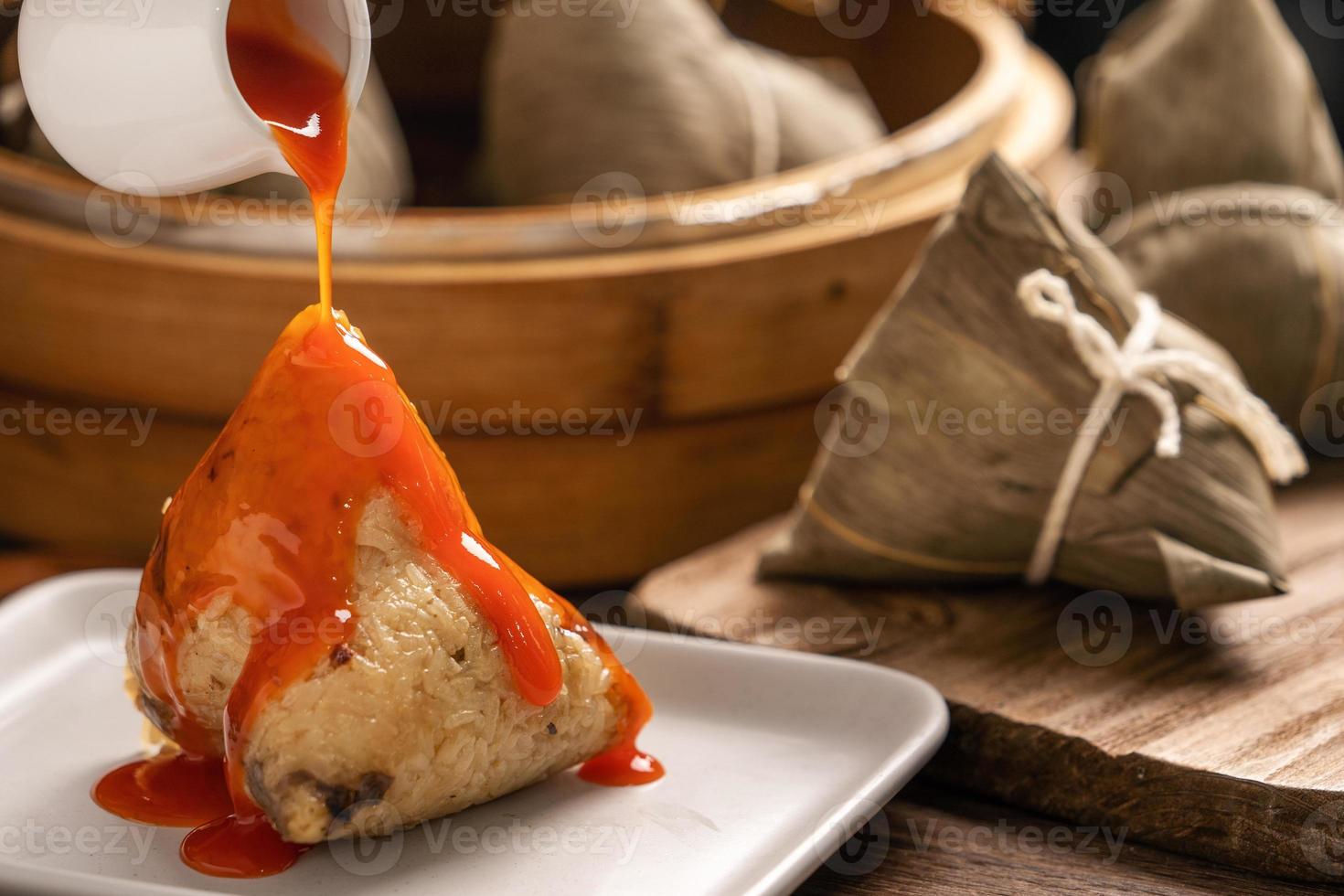 comendo zongzi - bolinho de arroz do festival do barco dragão jovem asiática comendo comida tradicional chinesa na mesa de madeira em casa celebração, close-up foto