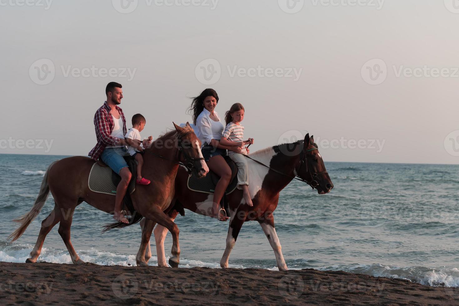 a família passa o tempo com seus filhos enquanto andam a cavalo juntos em uma praia de areia. foco seletivo foto