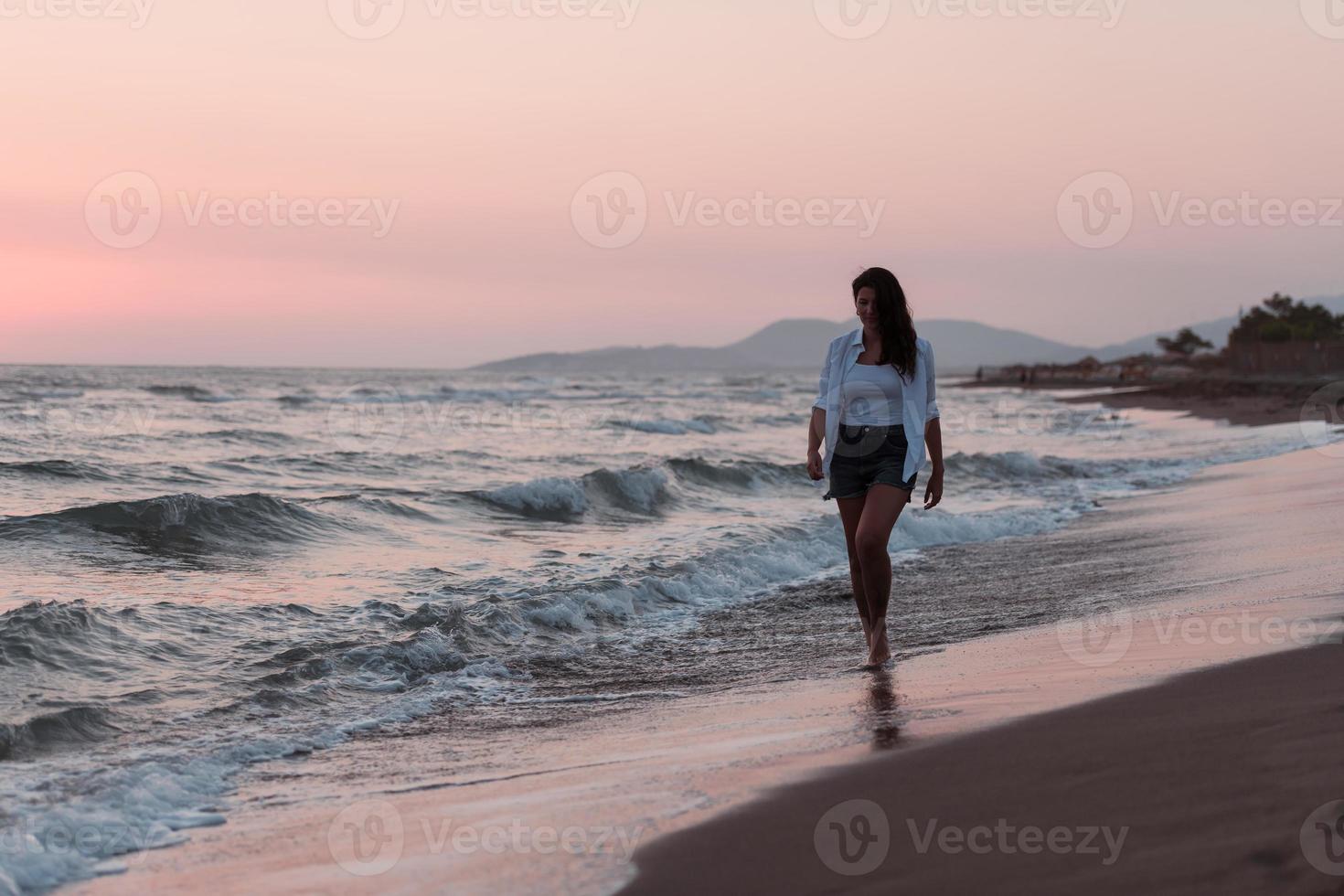 mulher despreocupada feliz apreciando o belo pôr do sol na praia. foco seletivo foto
