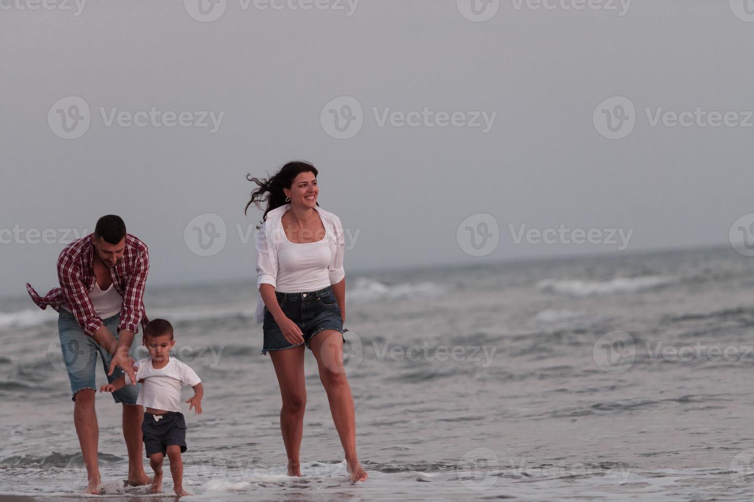 a família aproveita as férias enquanto caminham pela praia com o filho. foco seletivo foto