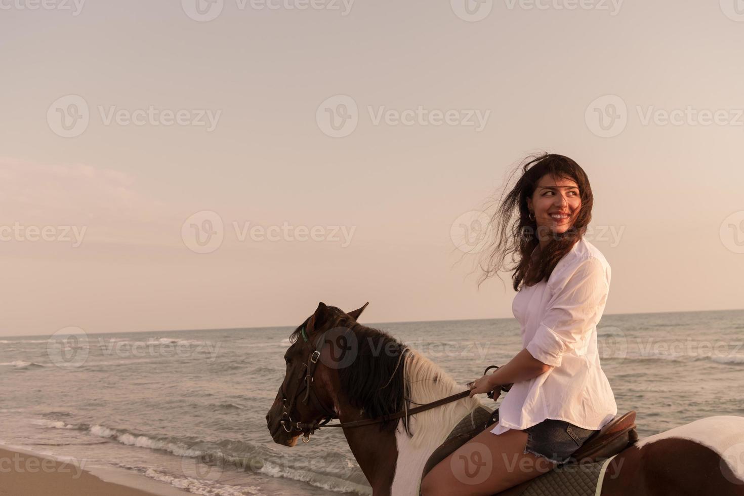 mulher com roupas de verão gosta de andar a cavalo em uma bela praia ao pôr do sol. foco seletivo foto