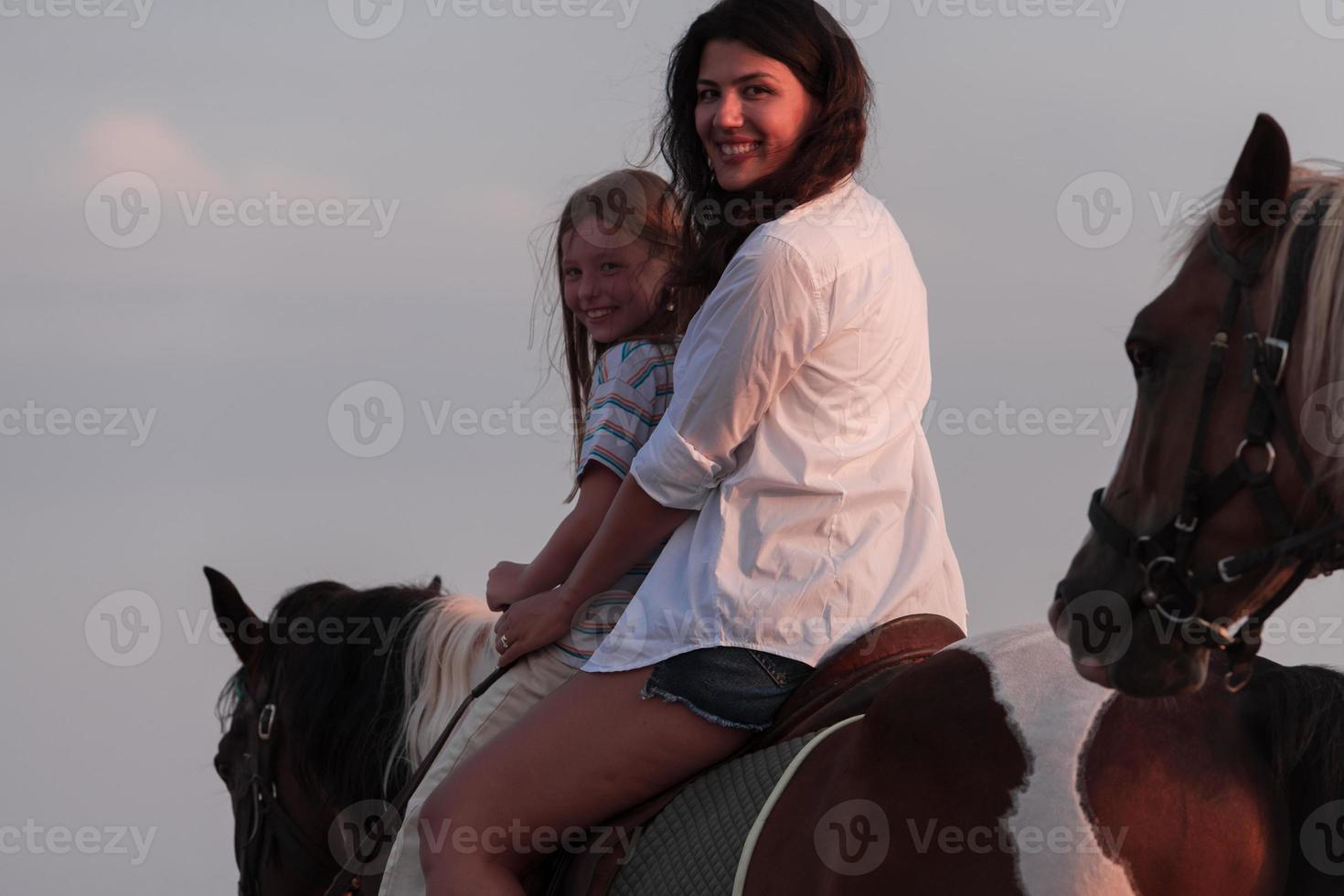 mãe e filha gostam de andar a cavalo juntos à beira-mar. foco seletivo foto