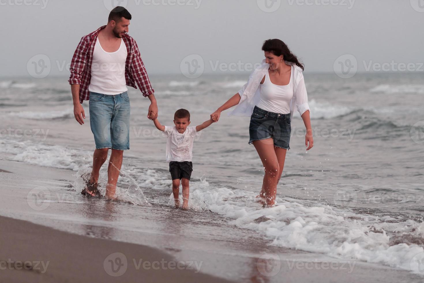 a família aproveita as férias enquanto caminham pela praia com o filho. foco seletivo foto