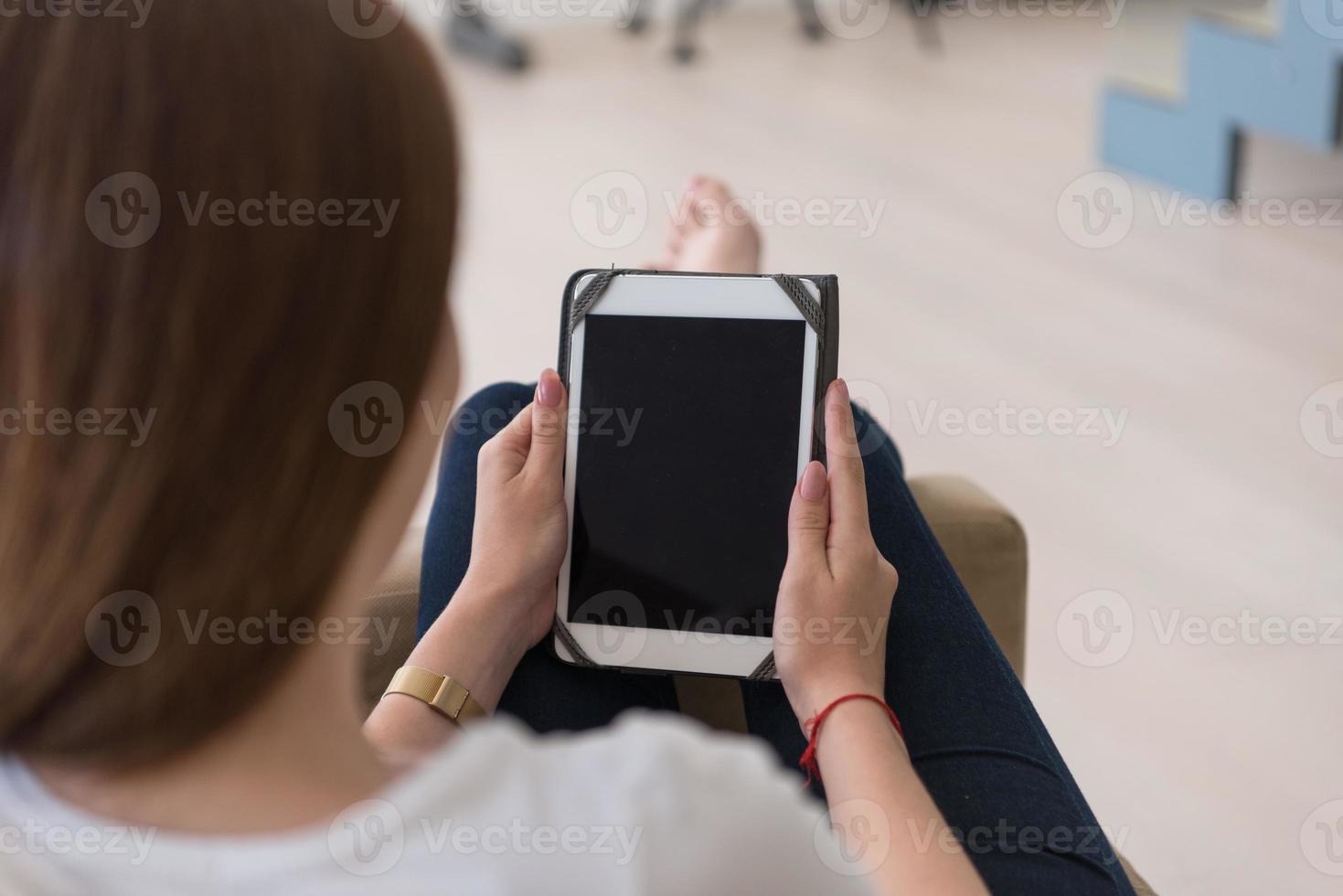 mulher sentada no sofá com computador tablet foto