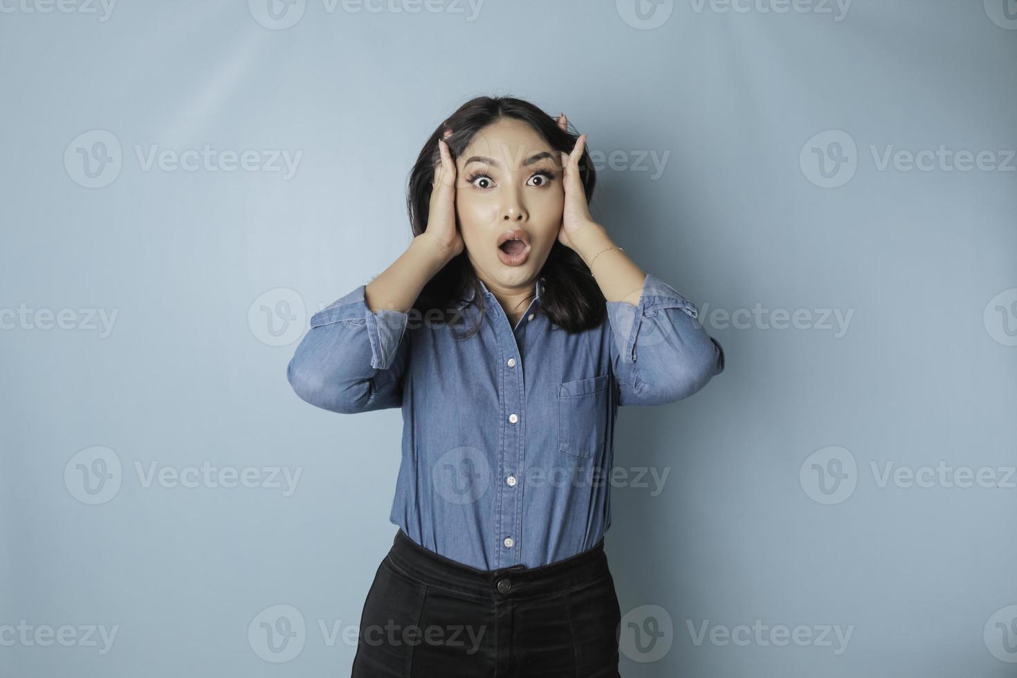 retrato de jovem mulher asiática isolado por fundo azul, sentindo-se frustrado com a expressão do rosto indefeso. foto