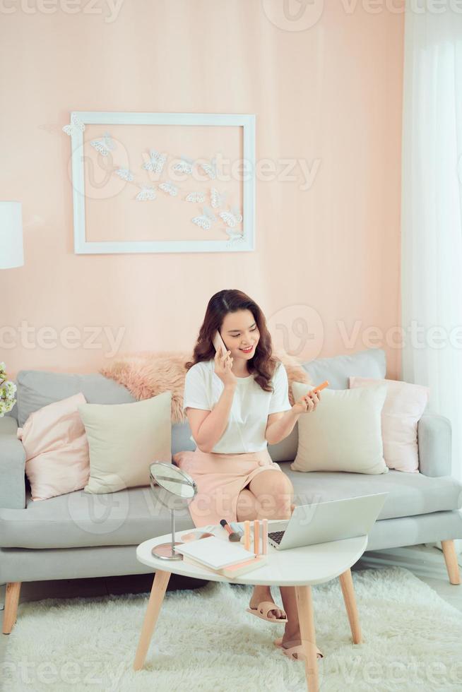 mulher aplicando seus cosméticos decorativos de maquiagem e falando no telefone. foto